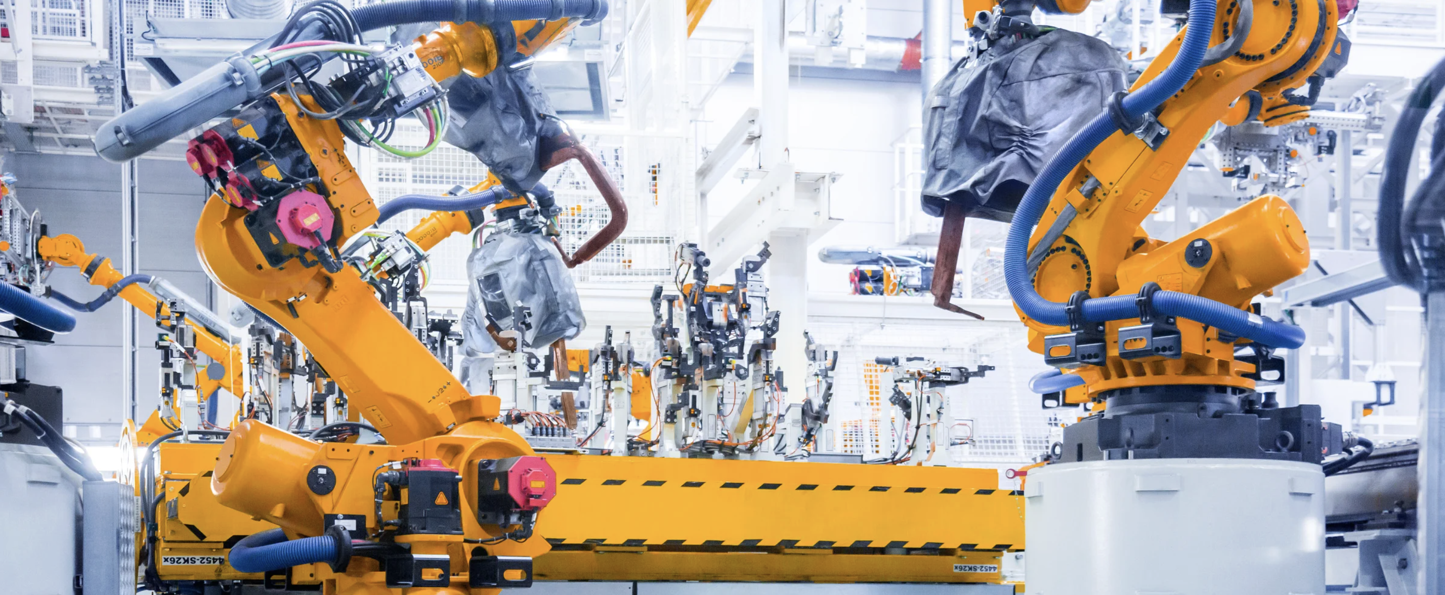 Manufacturing and Industrial: orange robotic arms working an automated assembly line in a bright modern factory